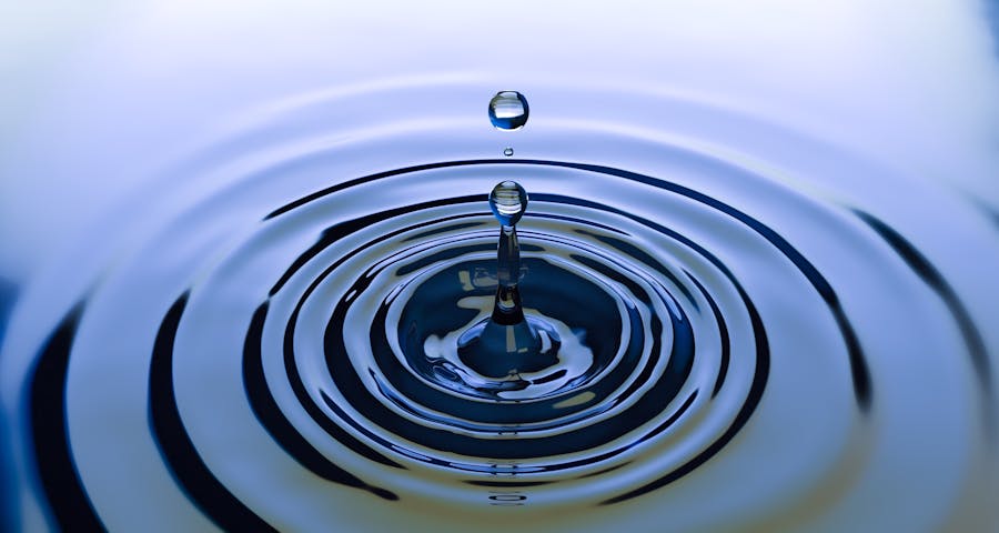 Water droplet rippling on a dark surface